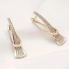Gold crystal drop earrings with modern sculptural twist design - earrings lay flat on display stand