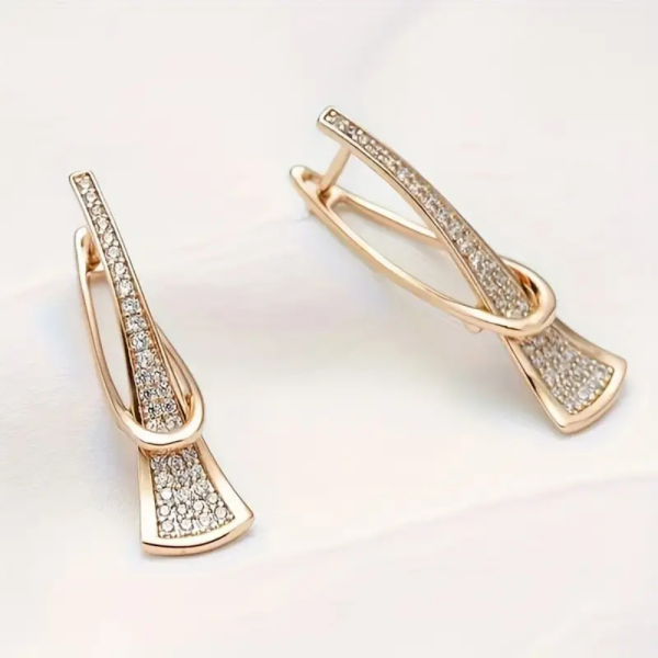 Gold crystal drop earrings with modern sculptural twist design - earrings lay flat on display stand