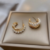 Gold huggie earrings with pearl detail and twist design - earring lay flat on display tray