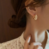 Gold huggie earrings with pearl detail and twist design - women using earrings 2