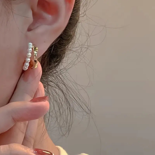 Gold huggie earrings with pearl detail and twist design - women using earrings